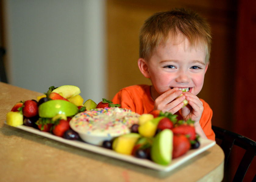 Happy boy eating fruit