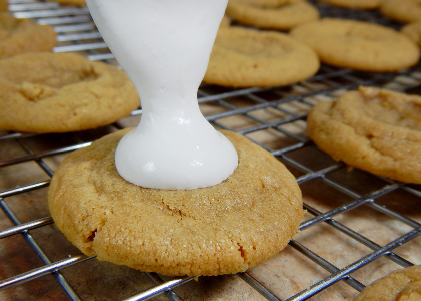 Pouring marshmallow fluff on a peanut butter cookie