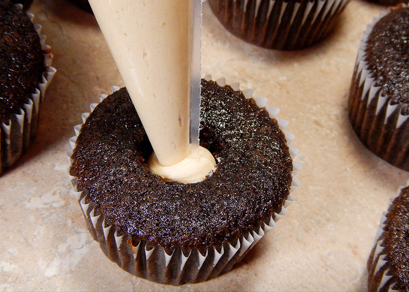 Piping peanut butter filling into chocoltae cupcakes