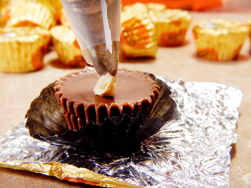 Piping frosting onto a mini peanut butter cup