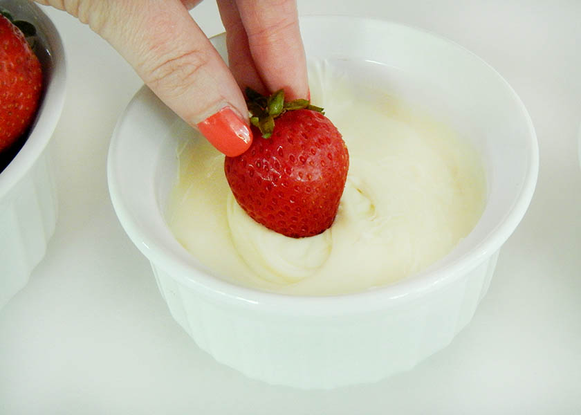 Dipping a rum-soaked strawberry in white candy melts
